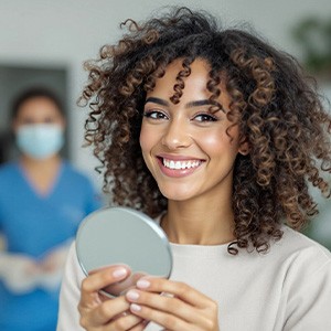 Woman smiling while holding small mirror