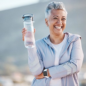 Woman smiling with water bottle on hike outside