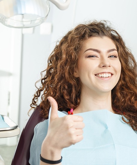 Female dental patient giving a thumbs up