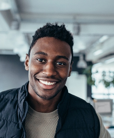 Man with vest standing in office and smiling