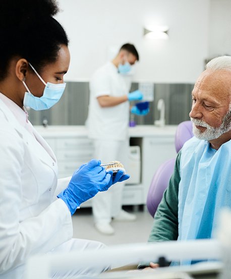 A dentist showing dentures to an older man