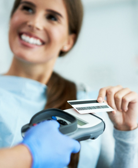 Smiling patient paying for treatment with credit card