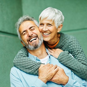 Husband and wife embracing with a green wall in the background
