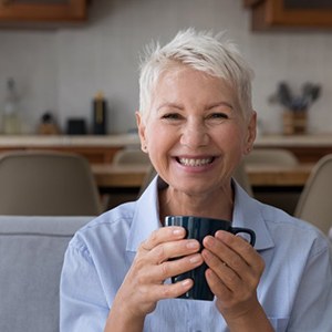 Woman smiling and enjoying a mug of coffee in her home