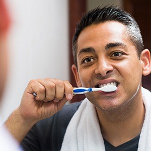 Man brushing teeth at mirror