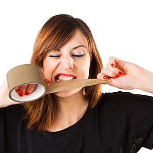 Woman tearing packing tape with her teeth