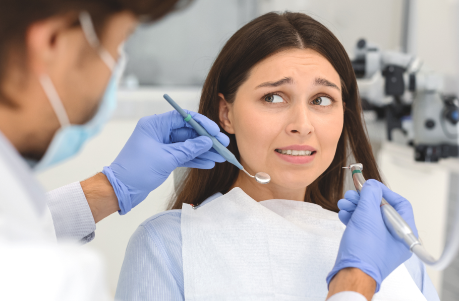 Woman in dental chair looking nervously at dentist